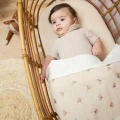 Baby in a crib with the Meyco Natural muslin sheet