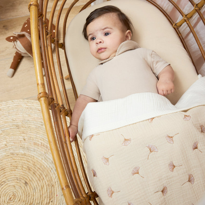 Baby in a crib with the Meyco Natural muslin sheet