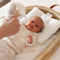 Baby resting on the Ko-Coon merino pillow in a Moses basket