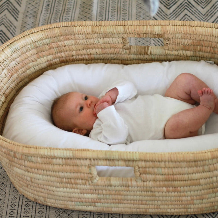 Baby in the Ko-Coon nesting pod inside a Moses basket
