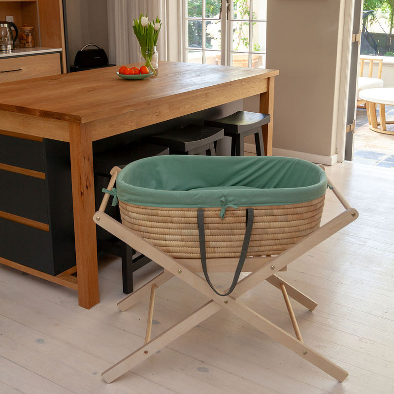 Ko-Coon foldable Moses stand with basket beside a table